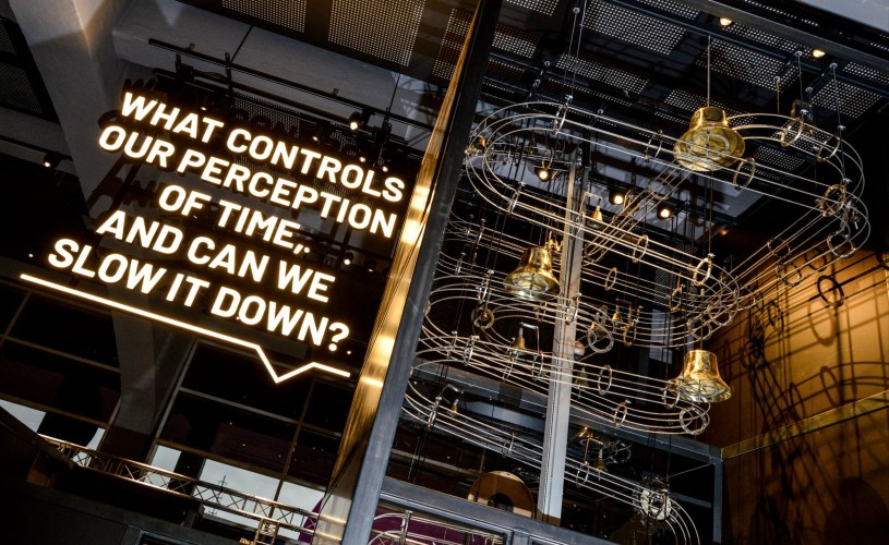 We The Curious exhibition with lit up text saying 'What controls our perception of time, and can we slow it down?' 